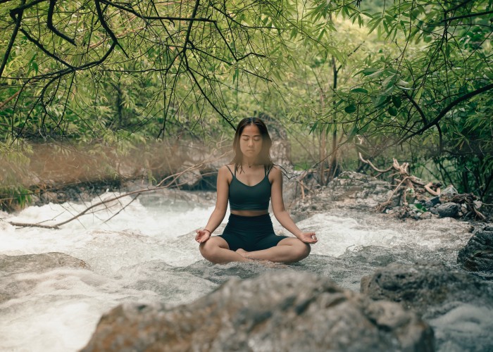 a woman sitting on a rock near a river